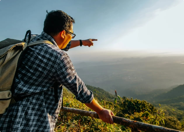 young asian hiker man with backpack standing point finger forward beautiful valley view view point with sunray sunset copy space